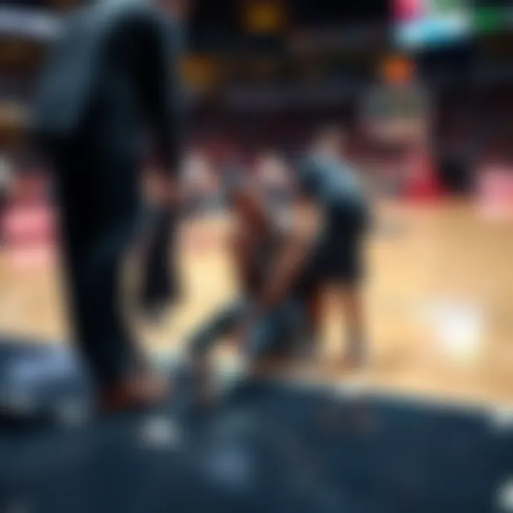 Derik Queen sitting on the basketball court while being attended to by trainers after his injury in the game