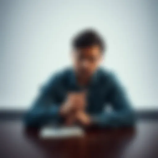 A person sits at a desk, looking contemplative with a notebook and pen in front of them, symbolizing the struggle with confidence.